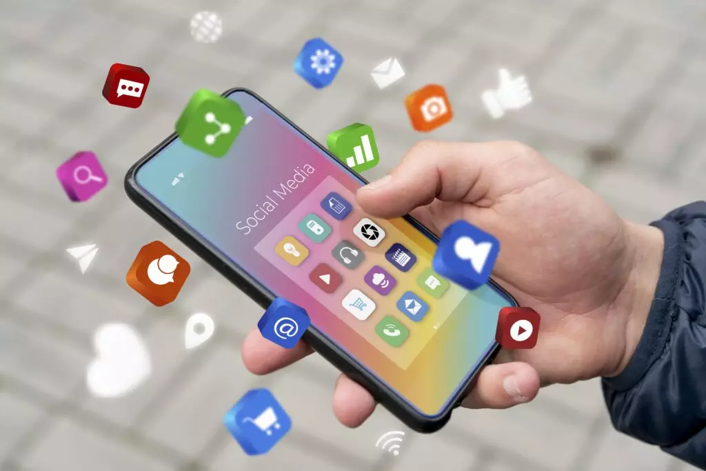 An image of a hand holding a phone with a bunch of app icons floating around the phone intended to represent mobile apps